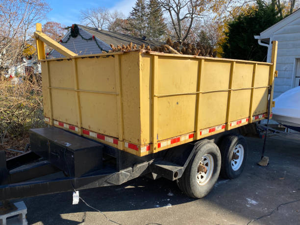 A portable rubbish yellow dumpster on a trailer in a residential homes driveway.